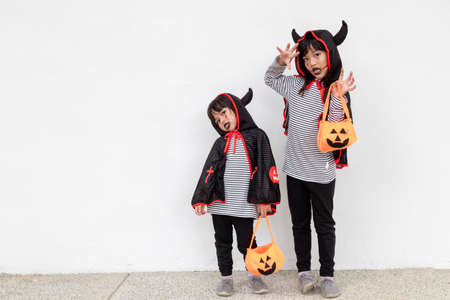 happy Halloween! two children in Halloween costumes and with pumpkins on white background