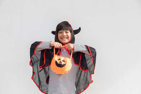 Funny halloween kid concept, little cute girl with costume halloween ghost scary he holding orange...