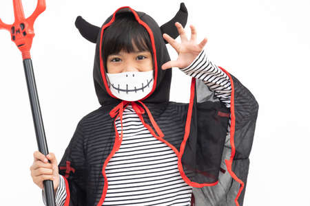 Asian little girl in a Halloween costume in a medical mask . Halloween with safety measures from...