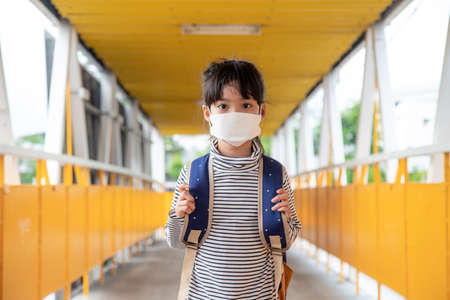 School child wearing a face mask during coronavirus and flu outbreak. Little girl going back to school after covid-19 quarantine and lockdown.の写真素材