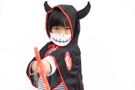 Asian little girl in a Halloween costume in a medical mask . Halloween with safety measures from Covid-19の写真素材