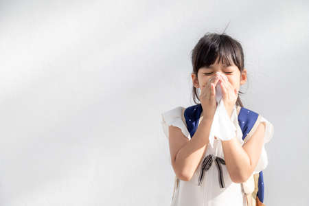 Asian child girl sick with sneezing on the nose and cold cough on tissue paper because weak or virus and bacteria from dust weatherの写真素材