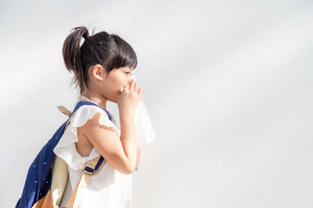 Asian child girl sick with sneezing on the nose and cold cough on tissue paper because weak or virus and bacteria from dust weatherの写真素材