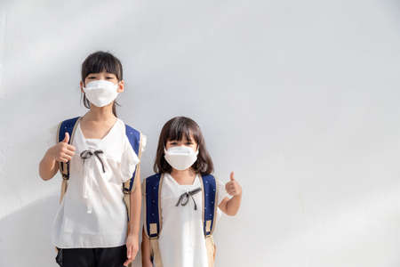 Sibling little girl wearing a mask to stop coronavirus outbreak.quarantine Asian sibling.covid-19 coronavirus and pandemic virus symptoms.の写真素材
