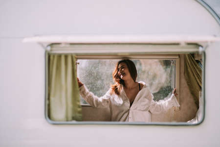 Beautiful young woman in a white shirt in the bedroom at homeの写真素材