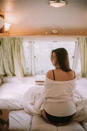 Beautiful young woman in a white shirt in the bedroom at home