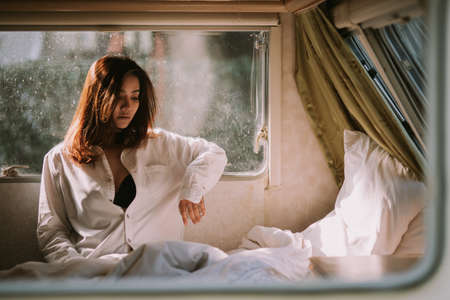 Beautiful young woman in a white shirt in the bedroom at home