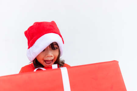 Happy Asian child in Santa red hat holding Christmas presents. Christmas time.on white background.の写真素材