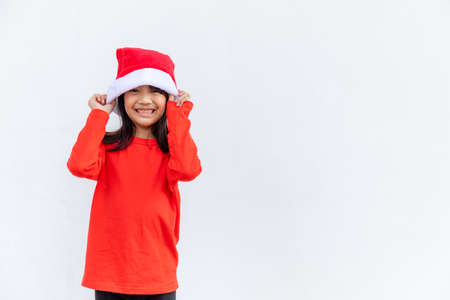 Asian little girl in red Santa hat on white background.の写真素材