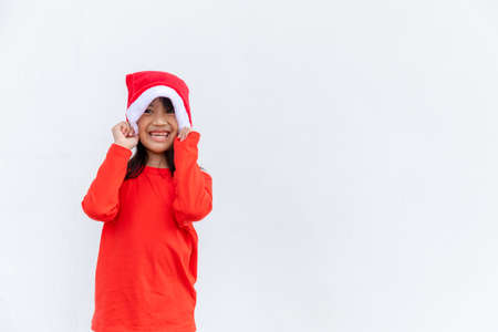 Asian little girl in red Santa hat on white background.の写真素材
