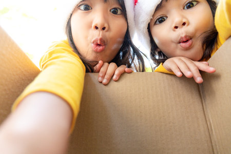 Surprised children unpack Christmas gift boxの写真素材
