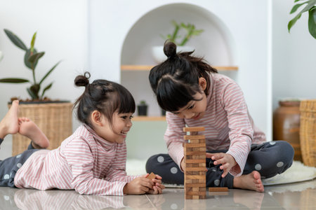Asian sibling  girl playing wooden stacks at homeの写真素材
