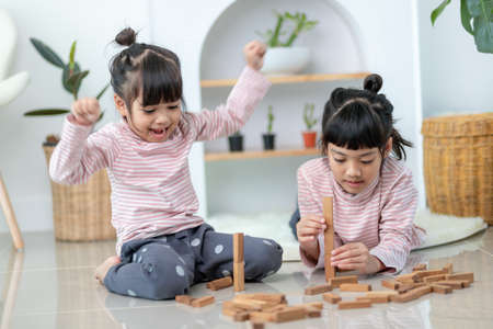 Asian sibling  girl playing wooden stacks at homeの写真素材