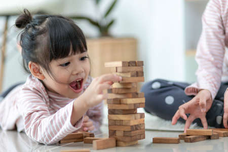 Asian sibling  girl playing wooden stacks at homeの写真素材