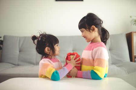 Merry Christmas happy sibling girls with a gift at homeの写真素材
