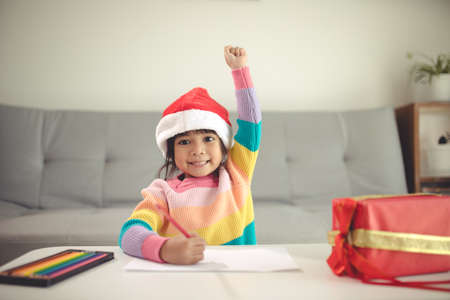 Christmas Child Write Letter to Santa Claus, Kid in Santa Hat Writing Wish Listの写真素材