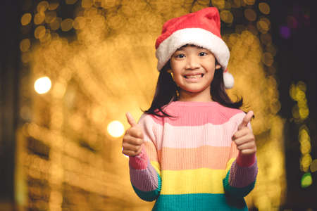 little girl in red Santa hat on bokeh background. portraitの写真素材