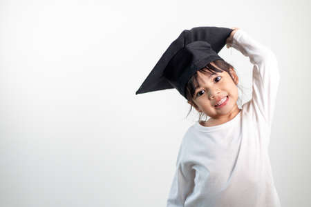 Happy Asian school kid graduate in graduation capの写真素材