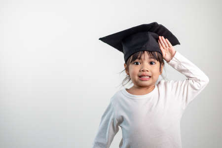 Happy Asian school kid graduate in graduation capの写真素材