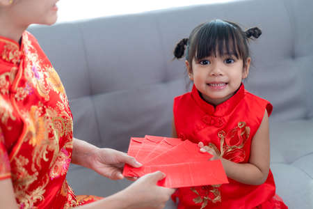 happy Asian little girl received red envelope from mother for Chinese new year
