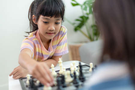 Little sibling girl playing chess at home.の写真素材