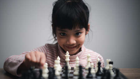 little girl playing a game of chess on a chessboard.