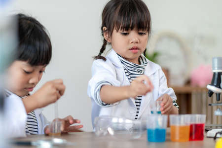 education, science, chemistry and children concept - kids or students with test tube making...