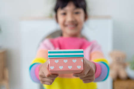 Little Asian girl smile and excited and holding red gift box in living room background. child holding gift box in Christmas and New year.Asian child girl smile and surprise.の写真素材