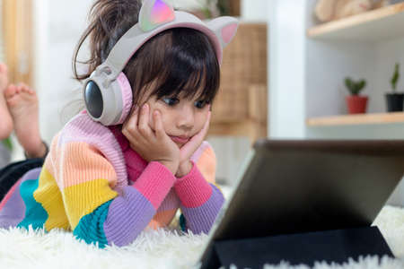 A Happy Asian little girl listening to music in the living-room
