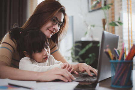 Mother working at home-office with daughter on her lapの写真素材