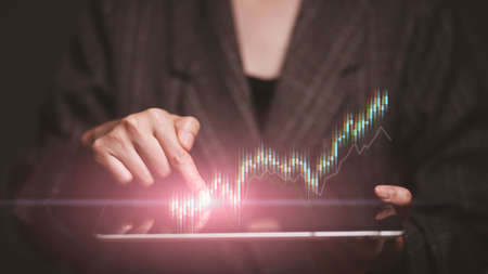 planning and strategy, Stock market, Business growth, progress or success concept. Hand of Businesswoman or trader is showing a growing virtual hologram stock on tablet, invest in tradingの写真素材