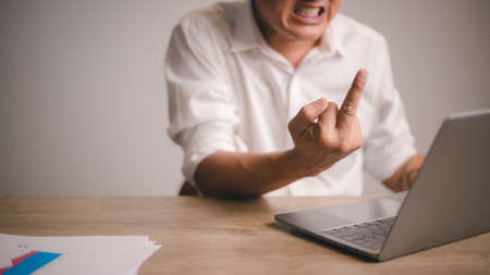 Fuck you. angry young big boss, working and making video call on a laptop, showing fucker and have...