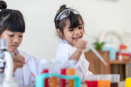 education, science, chemistry and children concept - kids or students with test tube making experiment at school laboratoryの写真素材