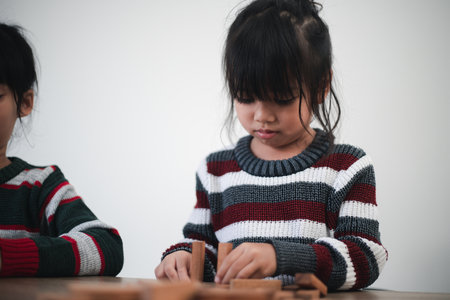 Cheerful Asian girl playing with wooden building blocks. Having fun and learning creativity. smart kid concept.の写真素材