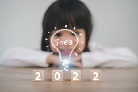 Wooden cubes with the numbers 2022 stand on the floor in a row. Background of a blurred happy girlの写真素材