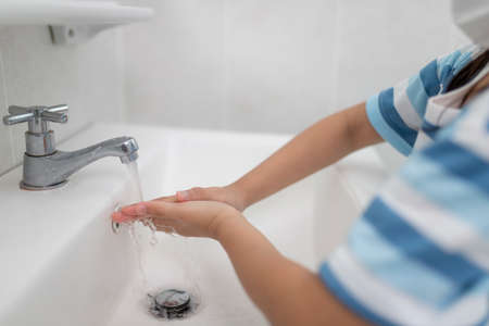 Little Asian girls wash their hands in the bathroom. Soft focus. Copy space.