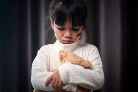 A child with the flag of Ukraine is crying. Sadness longing hope. Children's tears from the war. Evacuation of civilians. Freedom to Ukraineの写真素材