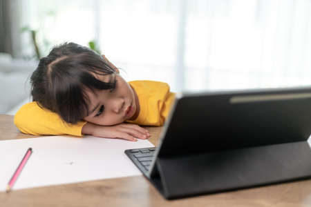 Little Asian girl sitting alone and looking out with a bored face, Preschool child laying head down...