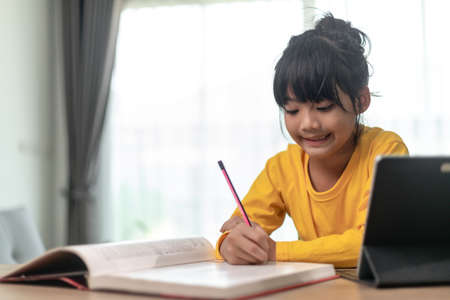 Asian little girl taking class on line and happy for Homeschool Quarantine coranavirus pandemic conceptの写真素材