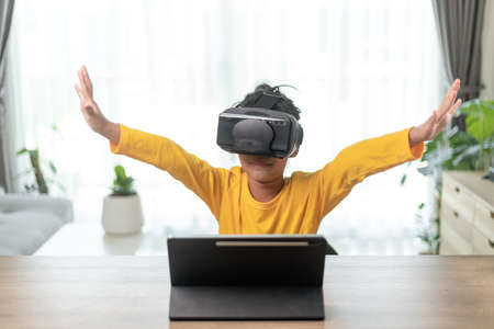 Cute girl wearing virtual reality googles at home, remote education experiment, future today, new online education, indoor lifestyleの写真素材