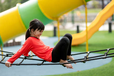 summer, childhood, leisure and people concept - happy little girl on children playground climbing frameの写真素材