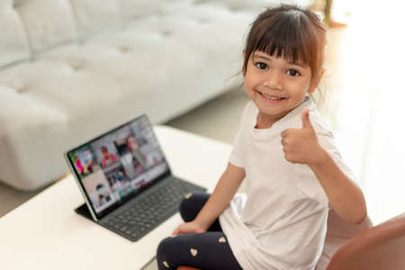 Asian little girl taking class on line and happy for Homeschool Quarantine coranavirus pandemic conceptの写真素材