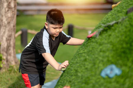 Child playing on outdoor playground. Kids play on school or kindergarten yard. Active kid on colorful slide and swing. Healthy summer activity for children. Little boy climbing outdoors.の写真素材