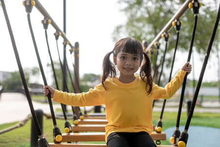 Cute little girl toddler having fun on the playground, climbing and sliding downの写真素材