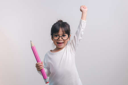 Excited young girl kid holding up big pencils in her hands.Back to school.の写真素材