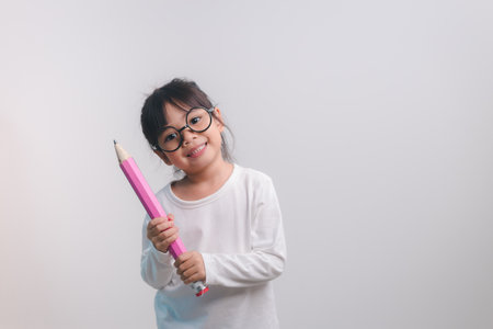 Excited young girl kid holding up big pencils in her hands.Back to school.の写真素材