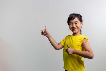 COVID 19 Vaccines for Kids concept. Studio a portrait of an adorable Asian girl after getting his...