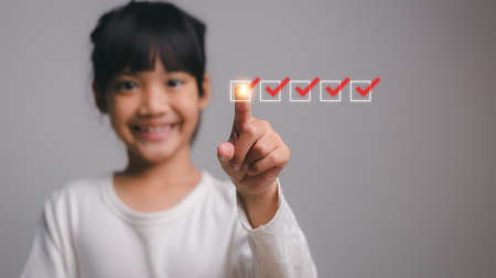 Cute little girl checking on checklist box. white background.の写真素材