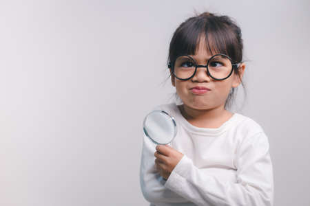 Little girl child holding a magnifying glass on white backgroundの写真素材