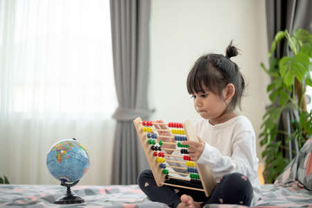 child kid  playing with abacus toy on bedの写真素材